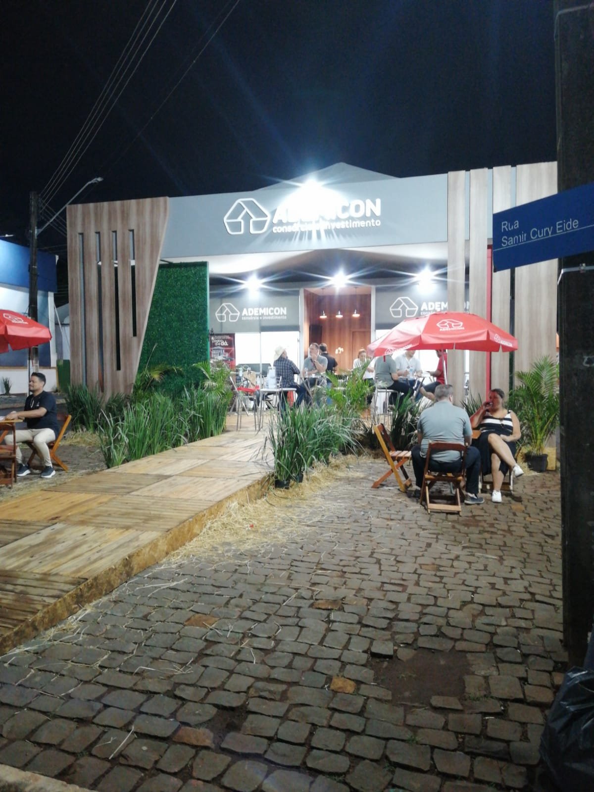 Estande da Ademicon iluminado à noite durante feira de negócios